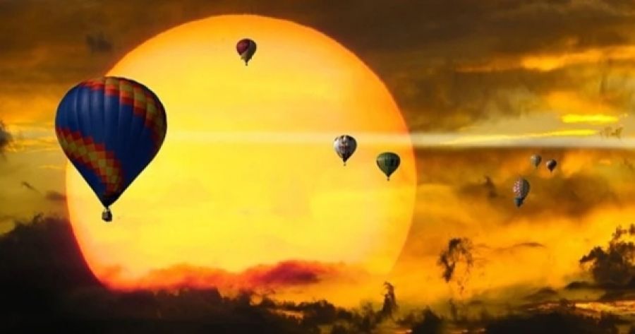 Un sol gigante y unos globos volando sobre el