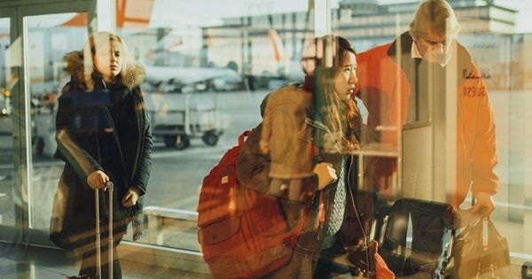 Personas guardando cola en un aeropuerto con maletas